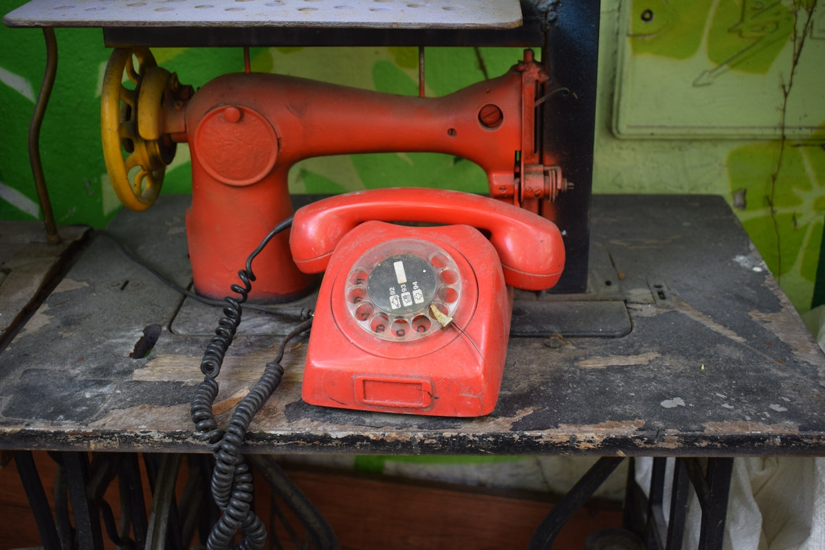 an old red telephone sitting on top of a table