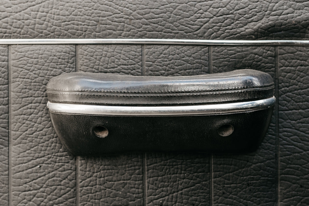 a close up of a leather seat with a metal handle