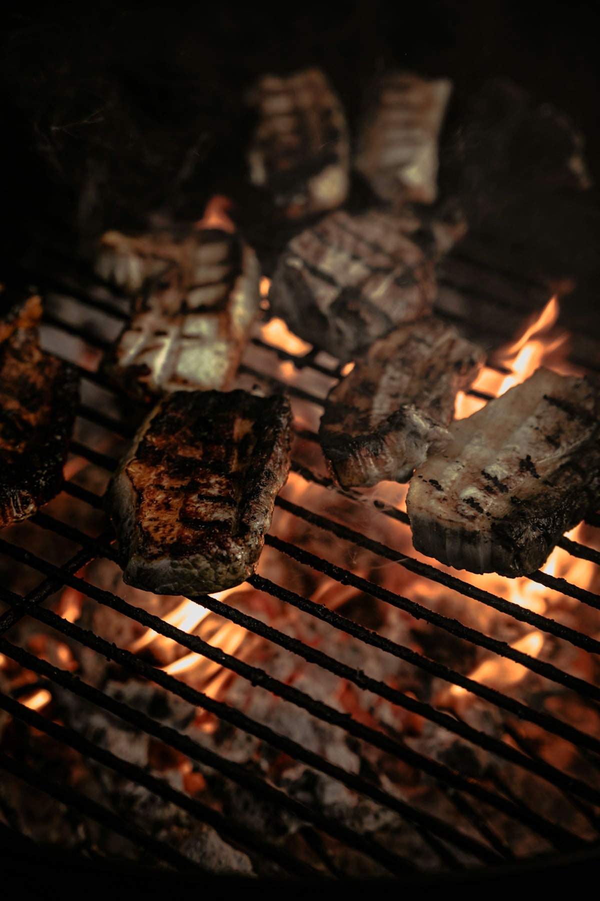 steaks cooking on a grill in the dark