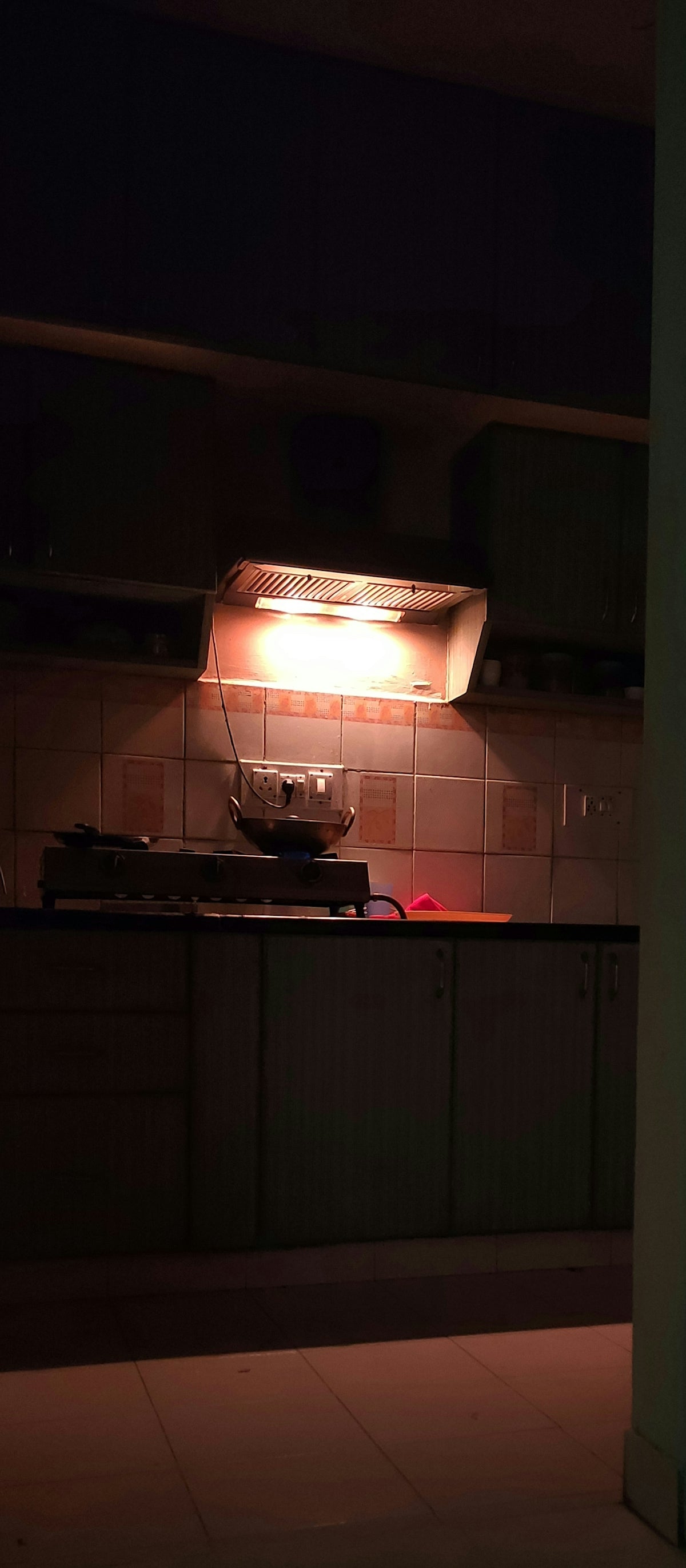 A kitchen with a stove top oven sitting under a light