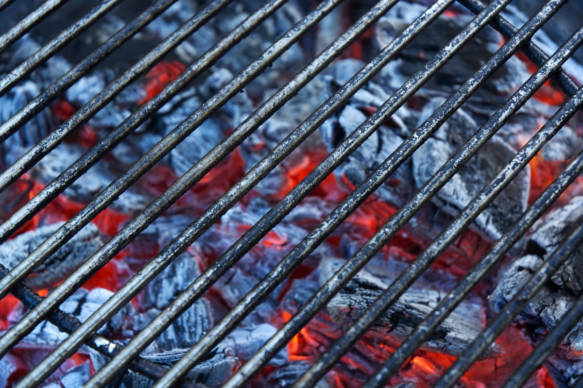 A charcoal grill grate with glowing embers.